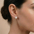 Side profile of a woman wearing large Edison pearl stud earrings, highlighting the round pearl silhouette and elegant ear styling.