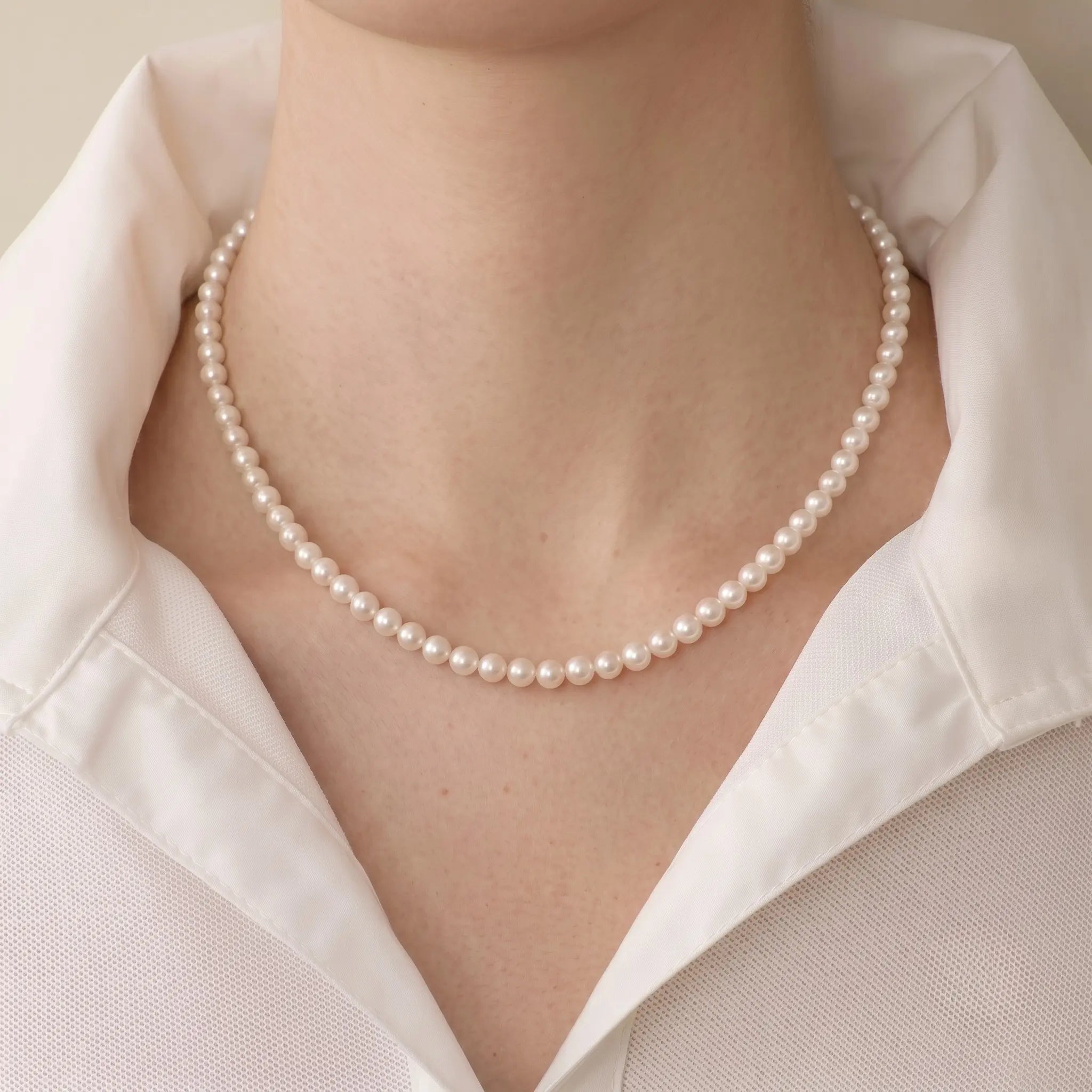 Woman wearing a solid gold freshwater pearl necklace and earrings set with a casual tee for effortless everyday polish.