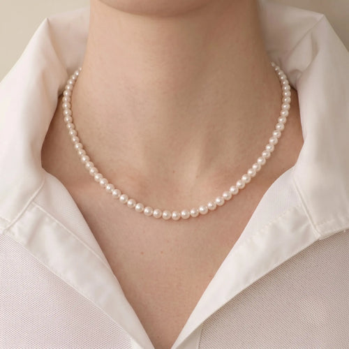 Woman wearing a solid gold freshwater pearl necklace and earrings set with a casual tee for effortless everyday polish.