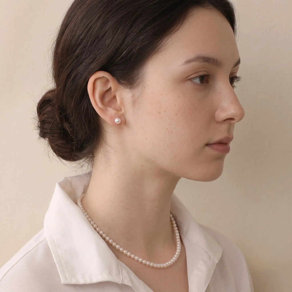 Close-up side profile of a woman wearing 18K white gold Tahitian pearl studs, showcasing the pearl’s unique peacock luster and refined elegance.