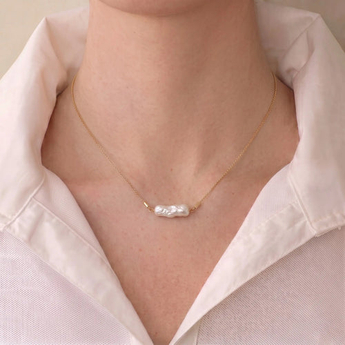Woman wearing an 18K solid gold Biwa pearl station necklace with organic pearls for a modern elegant jewelry look.