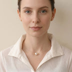 Lifestyle view of the minimalist floating pearl necklace layered with multiple solid 18K gold chains on a model.