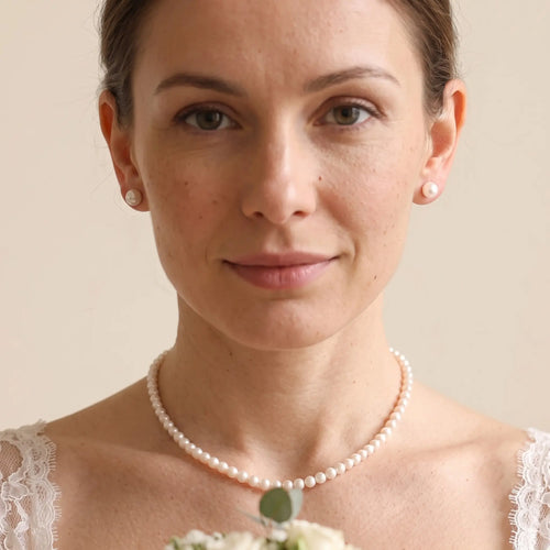 Elegant woman wearing a freshwater pearl necklace and earrings set for a timeless bridal or special occasion look.