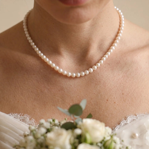 Front view of a bride wearing the classic 7-7.5mm freshwater pearl choker necklace with an elegant wedding gown.