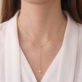 Woman wearing an 18K solid gold rice pearl Y-lariat necklace for an elegant neckline-enhancing jewelry look.