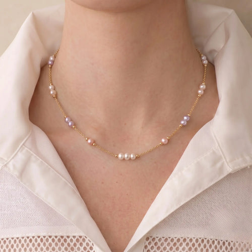 Woman wearing an 18K solid gold multicolor pearl station necklace for a chic everyday French-inspired jewelry look.