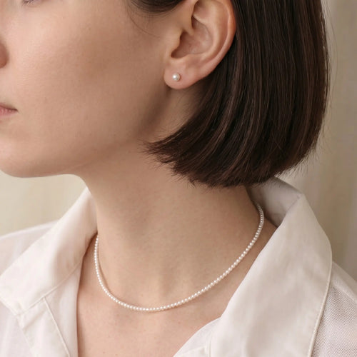 Woman wearing solid 18K white gold Tahitian pearl earrings from a side view, emphasizing the minimalist yet luxurious design.