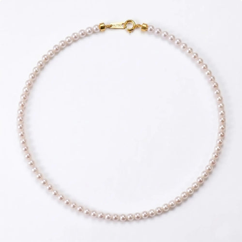 Onepearlife continuous seed pearl strand necklace flat lay on a stark white studio background, showcasing a seamless ribbon of 2mm mini pearls closely nestled without gold spacers.