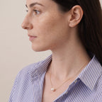 High-resolution studio photo of a minimalist Akoya pearl necklace, showcasing the pearl's mirror-like sharp reflection and intense metallic sheen against a clean white surface.