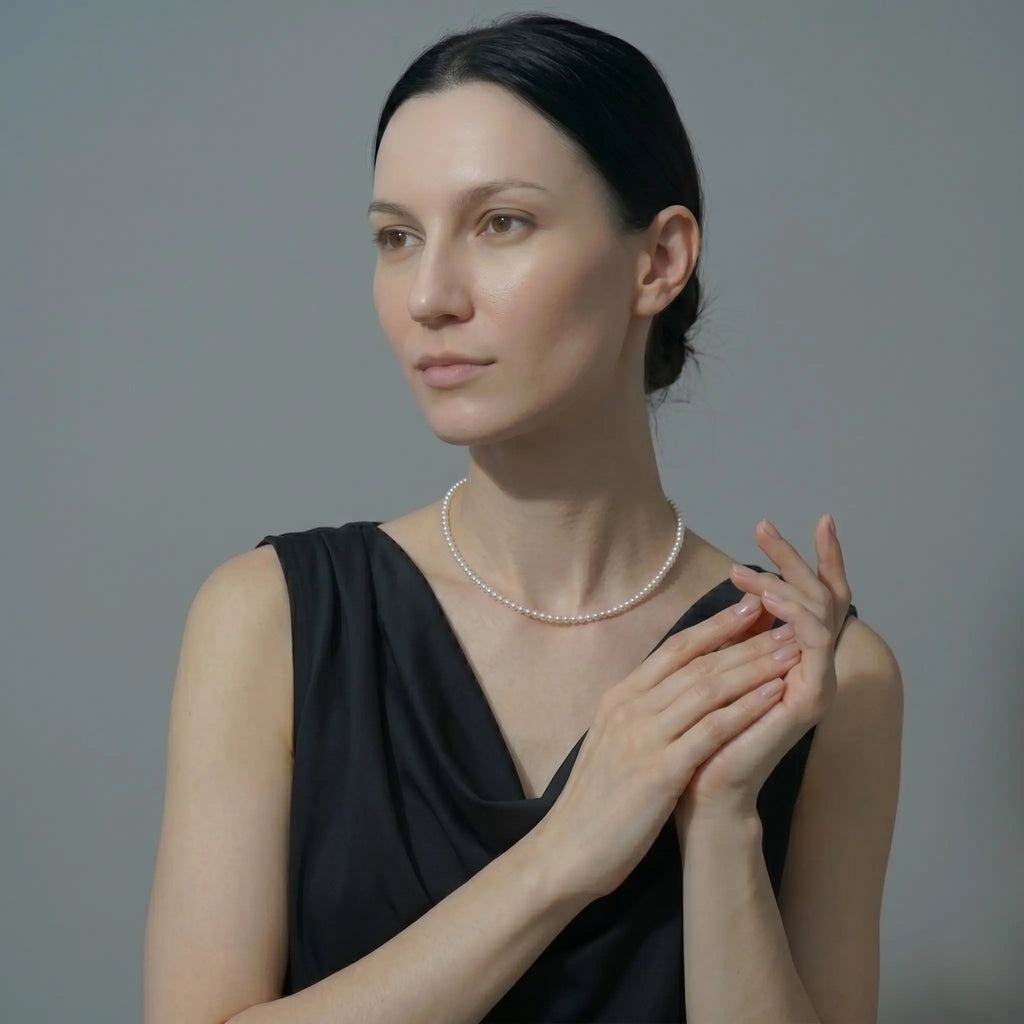 Woman wearing a pearl necklace against a gray background