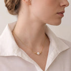 Detail shot of a model’s neck and clavicle, accessorized with a subtle and elegant 18K solid gold floating pearl pendant, illustrating a versatile look.