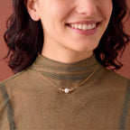 A delicate 18k solid yellow gold floating-style solitaire pearl necklace resting on the collarbone, emphasizing a tarnish-free and hypoallergenic finish for lifetime wear.