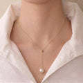 Front view of a model wearing the elongating 18K gold Y-shaped pearl necklace, showcasing a slimming neckline effect.