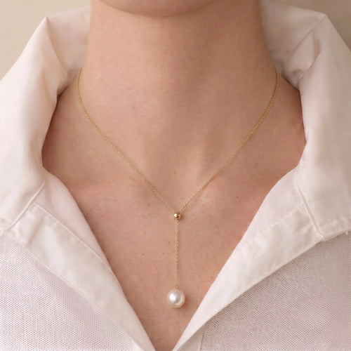 Front view of a model wearing the elongating 18K gold Y-shaped pearl necklace, showcasing a slimming neckline effect.