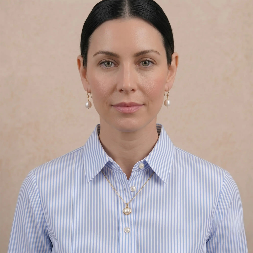 Front view of model wearing white button down shirt and 18k solid gold baroque pearl earrings