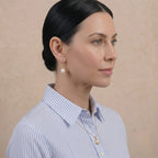 Side profile of model in casual shirt wearing mirror luster baroque pearl gold earrings