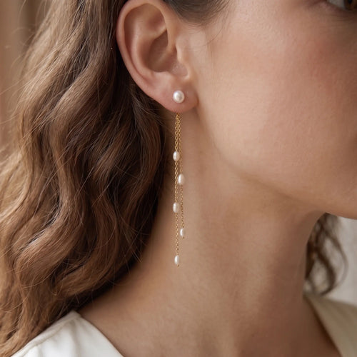 Front view of a professional woman wearing an unbuttoned white shirt, styled with 18k solid gold fluid twin-line rice pearl tassel earrings for an elegant everyday look.
