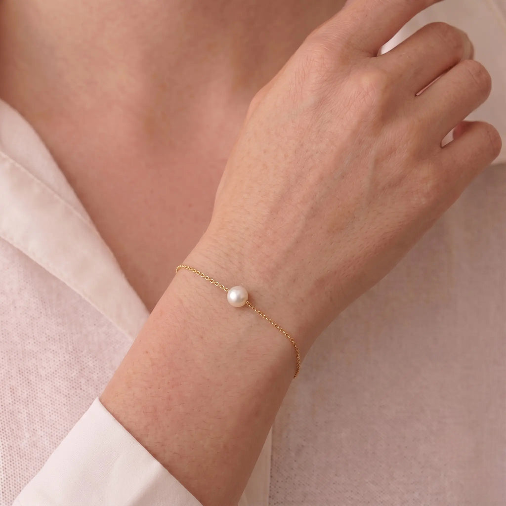 Side profile of a model's finger wearing the Akoya pearl moon ring, detailing the artisanal wavy brushed-gold texture and adjustable open-shank design.