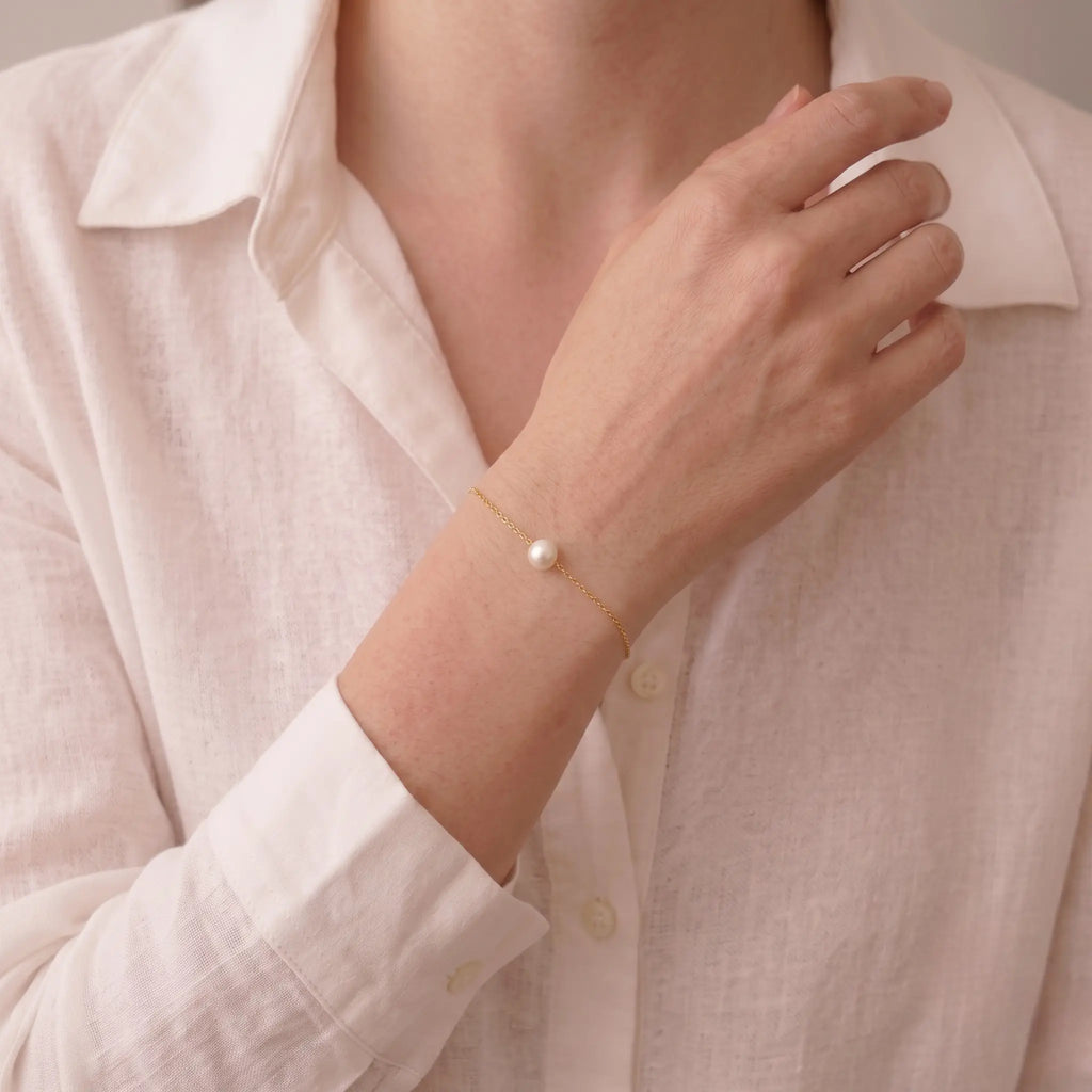 Close-up shot of a professional woman styling the 7-7.5mm Akoya gold bracelet with office attire, illustrating its skin-brightening radiance.