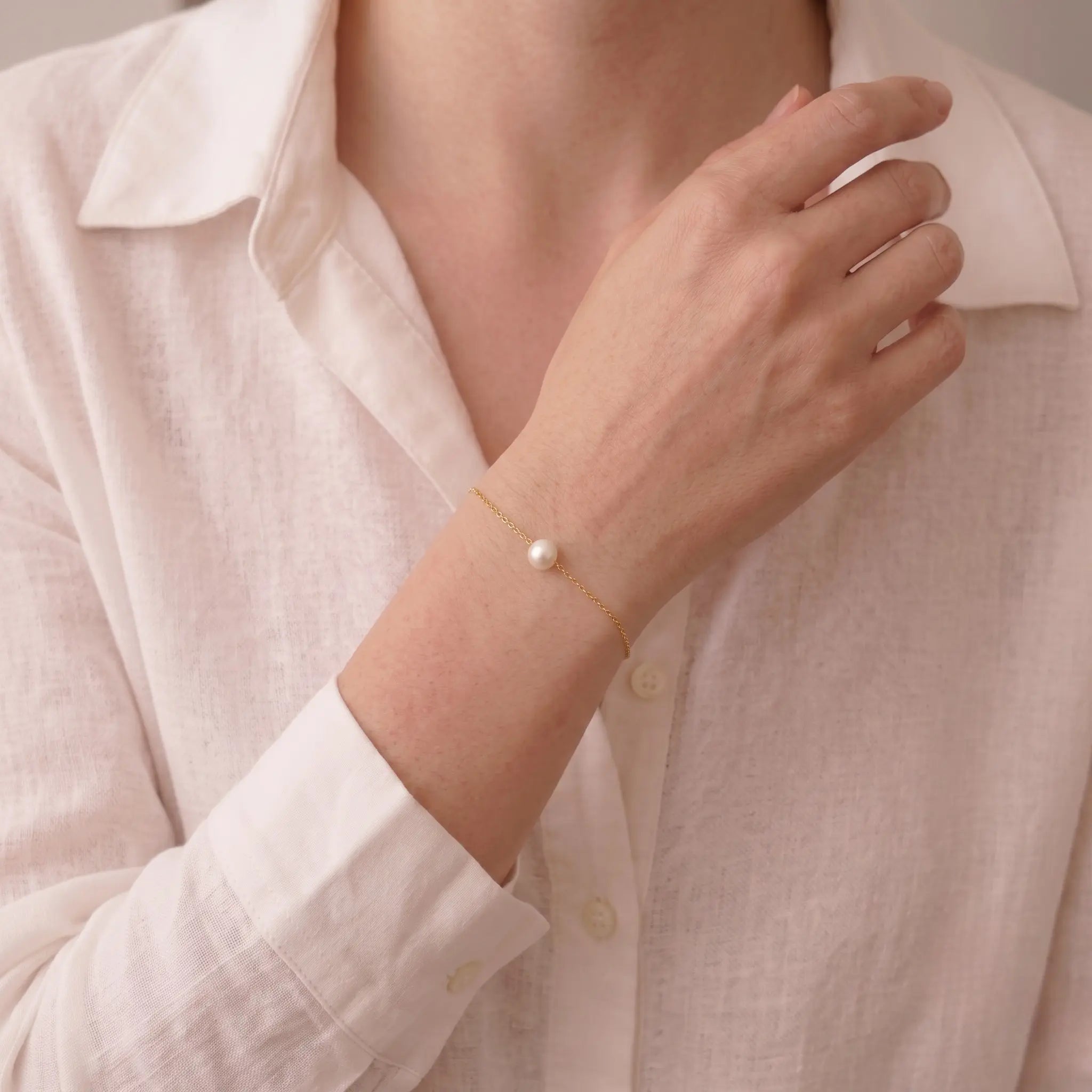Close-up shot of a professional woman styling the 7-7.5mm Akoya gold bracelet with office attire, illustrating its skin-brightening radiance.