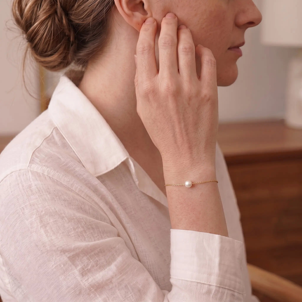 Front view of a model's wrist wearing the minimalist single Japanese Akoya pearl bracelet on an ultra-fine 18K solid gold chain, showcasing its iconic mirror-like luster.