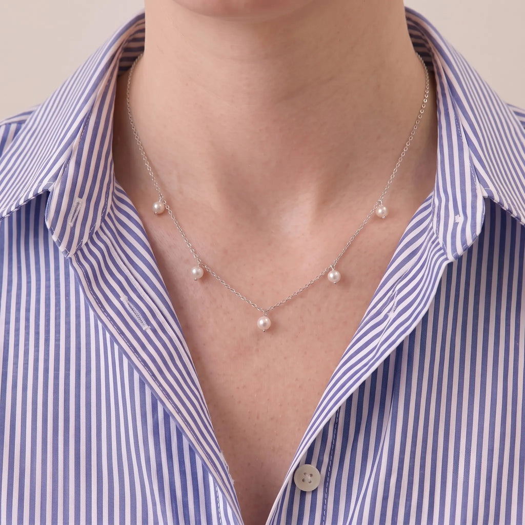 A woman wearing an unbuttoned white tailored shirt paired with a cascading S925 sterling silver V-shape pearl necklace for a sleek, professional daily outfit.