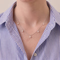 A woman wearing an unbuttoned white tailored shirt paired with a cascading S925 sterling silver V-shape pearl necklace for a sleek, professional daily outfit.