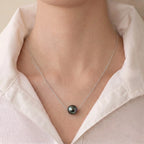 Front view of a model wearing the commanding 10-10.5mm Tahitian black pearl necklace on her collarbone.