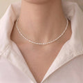 Woman wearing a mini freshwater seed pearl necklace for a French-chic minimalist jewelry look.