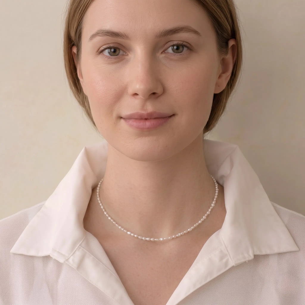 Woman wearing a mini freshwater seed pearl necklace for a French-chic minimalist jewelry look.