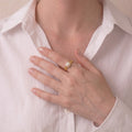 Top-down view of a woman's hand wearing the Golden Lunar Muse ring, showcasing the mirror-like 7-7.5mm Akoya pearl cradled in a sparkling CZ crescent moon.