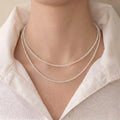 Model wearing a quiet luxury layered pearl necklace inside a tailored executive silk shirt, demonstrating a powerful, composed professional presence.