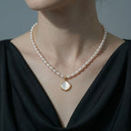 An AAA lustre white rice pearl necklace featuring a delicate shell pendant.