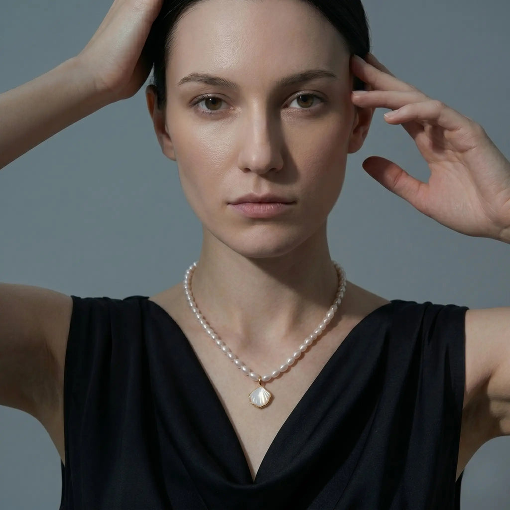 A model wearing a layering AAA rice pearl necklace with a seashell pendant for a beach-inspired look