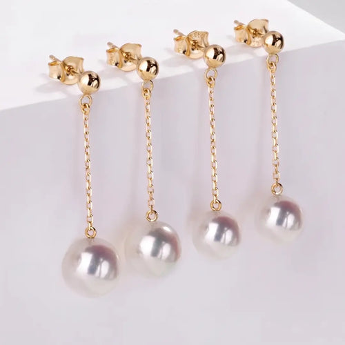 Studio still life of a pair of minimalist long fluid Akoya pearl chain drop earrings crafted in solid 18K yellow gold, focusing on the sleek vertical silhouette.