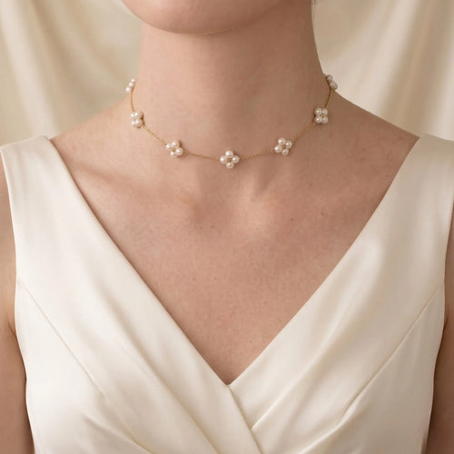 Close-up of a bride in an elegant lace wedding dress, showcasing the romantic silhouette of an 18K solid gold pearl station necklace with a unique berry layout.