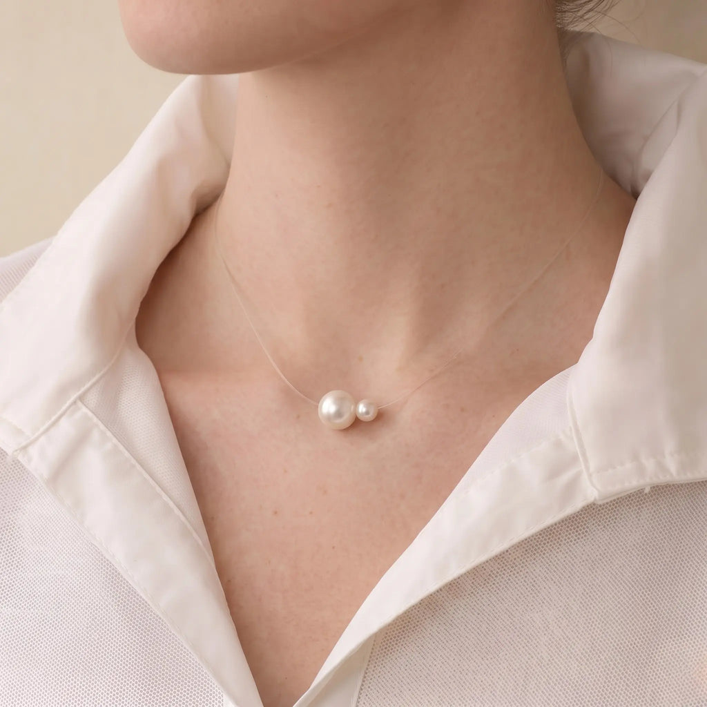 A close-up of a model's collarbone wearing a floating double pearl necklace, showing the 5mm and 7.5mm pearls appearing to float directly on the skin.