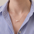 Front view of a model wearing an asymmetric twin Akoya pearl necklace with a crisp white linen shirt, modern luxury everyday lifestyle styling.
