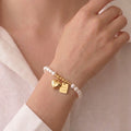 Woman wearing a baroque rice pearl charm bracelet with heart and Good Luck charms for a modern elegant jewelry look.