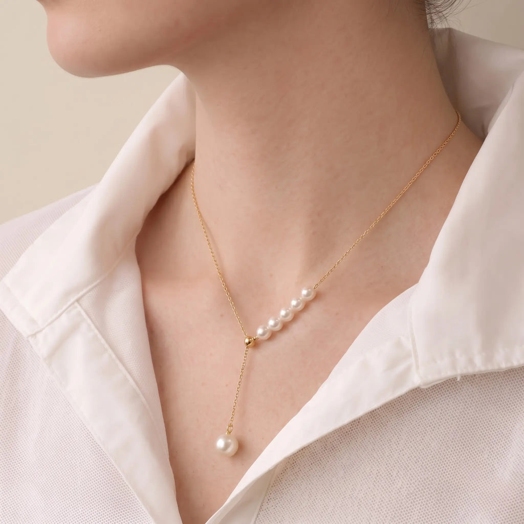 Detailed shot of a model wearing the Onepearlife poetic pearl duo pendant, showcasing how the iconic rose-pink overtones of the Akoya pearls instantly brighten the skin tone.