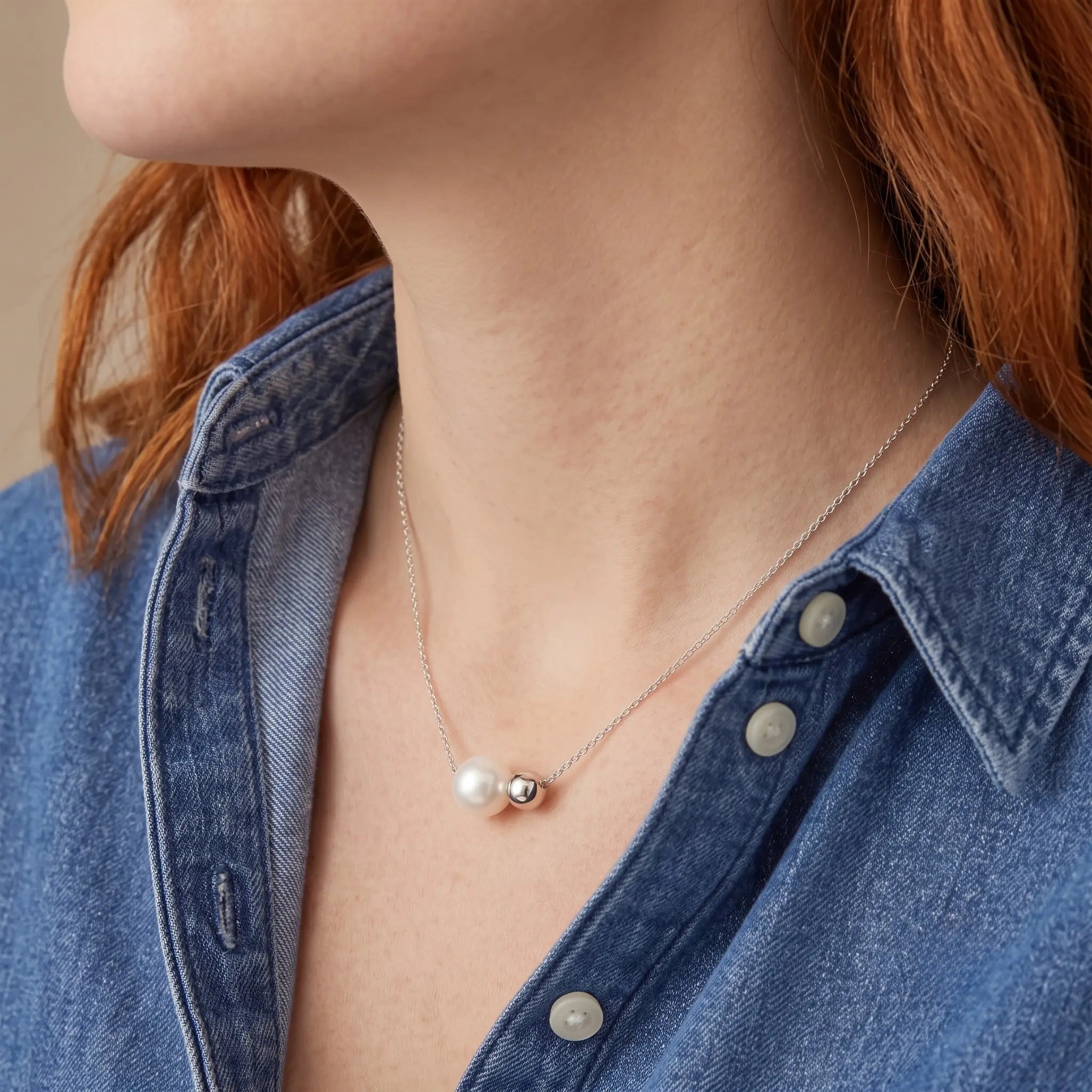 Side profile of a woman wearing the versatile 18K white gold plated asymmetrical jewelry paired with a sharp blazer.