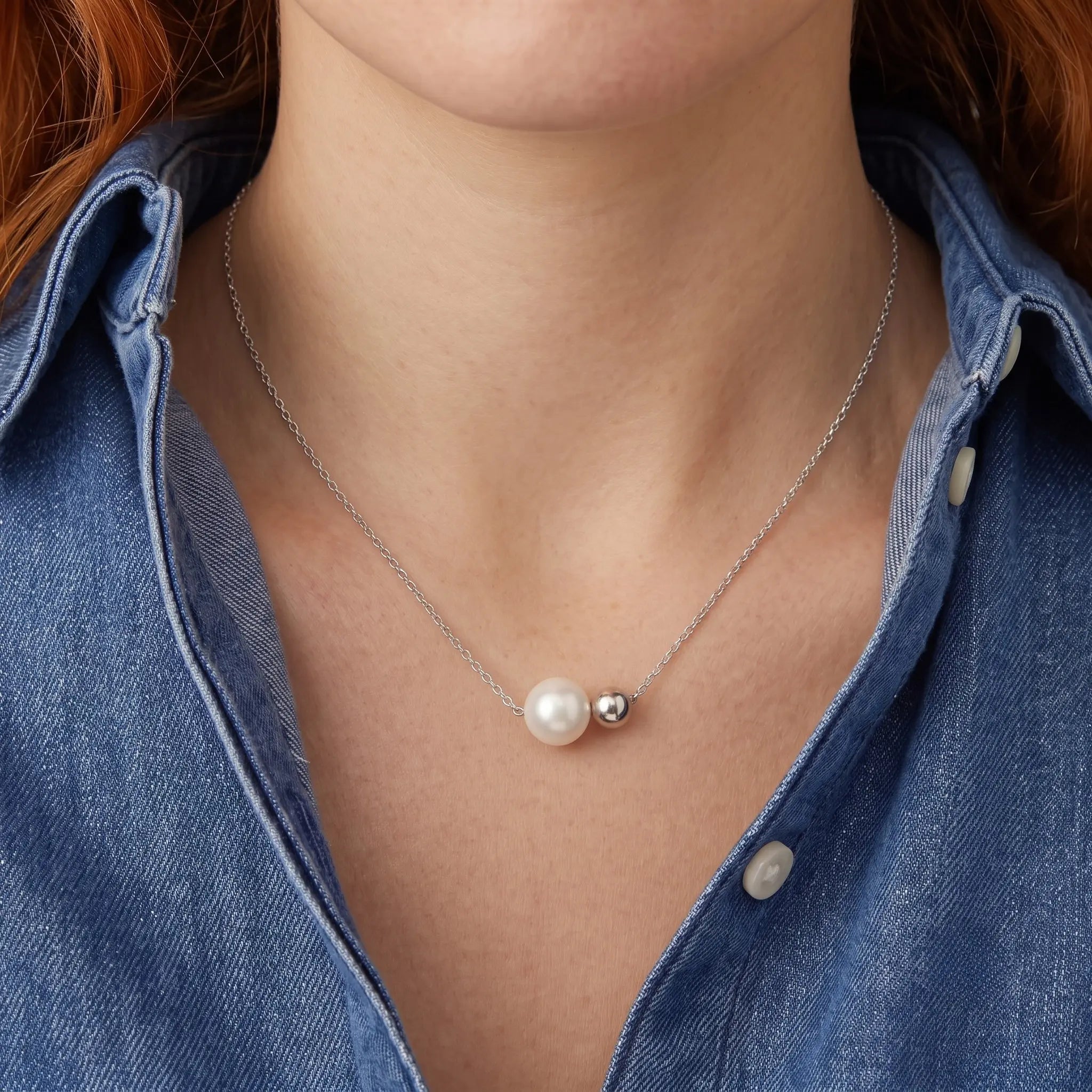Front view of a model wearing the asymmetrical minimalist necklace with a casual denim shirt for a modern everyday look