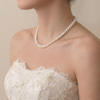 ide view of a modern bride in her wedding gown wearing a high-character offset layout pearl necklace for a unique bridal look.